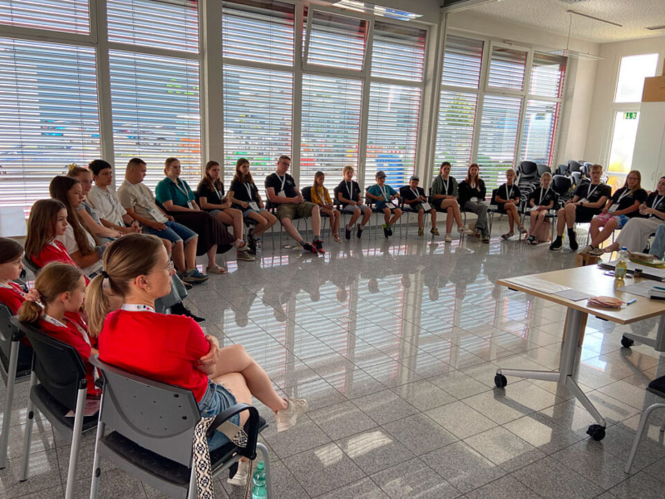 Kinder und Jugendliche sitzen im Kreis bei der JRK-Kinderversammlung.